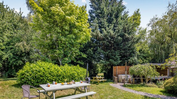 Ein Picknickbereich mit Tisch und Bänken, umgeben von üppiger Vegetation und Bäumen.
