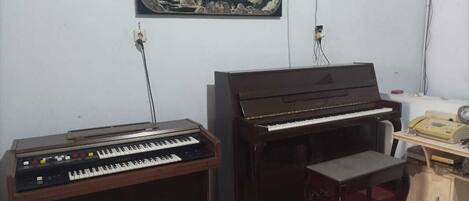A room with a piano, a keyboard, and a desk with a telephone.