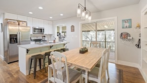 A modern kitchen with a central island, stainless steel appliances, and a large window overlooking a deck. - Bella's Vista - Hound Dog Haven (Bella Vista)