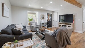 A modern living room with a grey sofa, a coffee table, and a television. - Bella's Vista - Hound Dog Haven (Bella Vista)