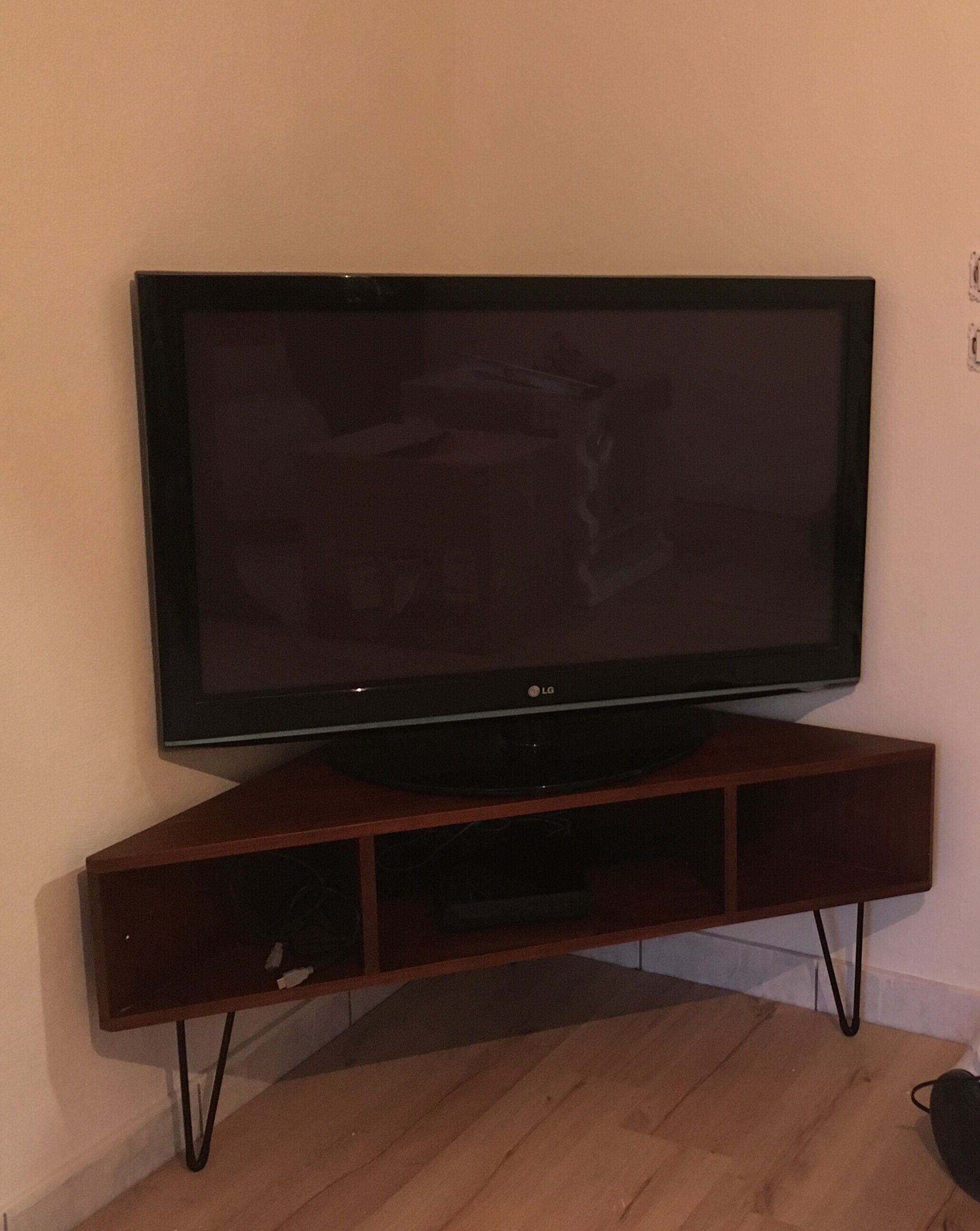 A flat-screen TV on a wooden TV stand with a cable management box underneath.