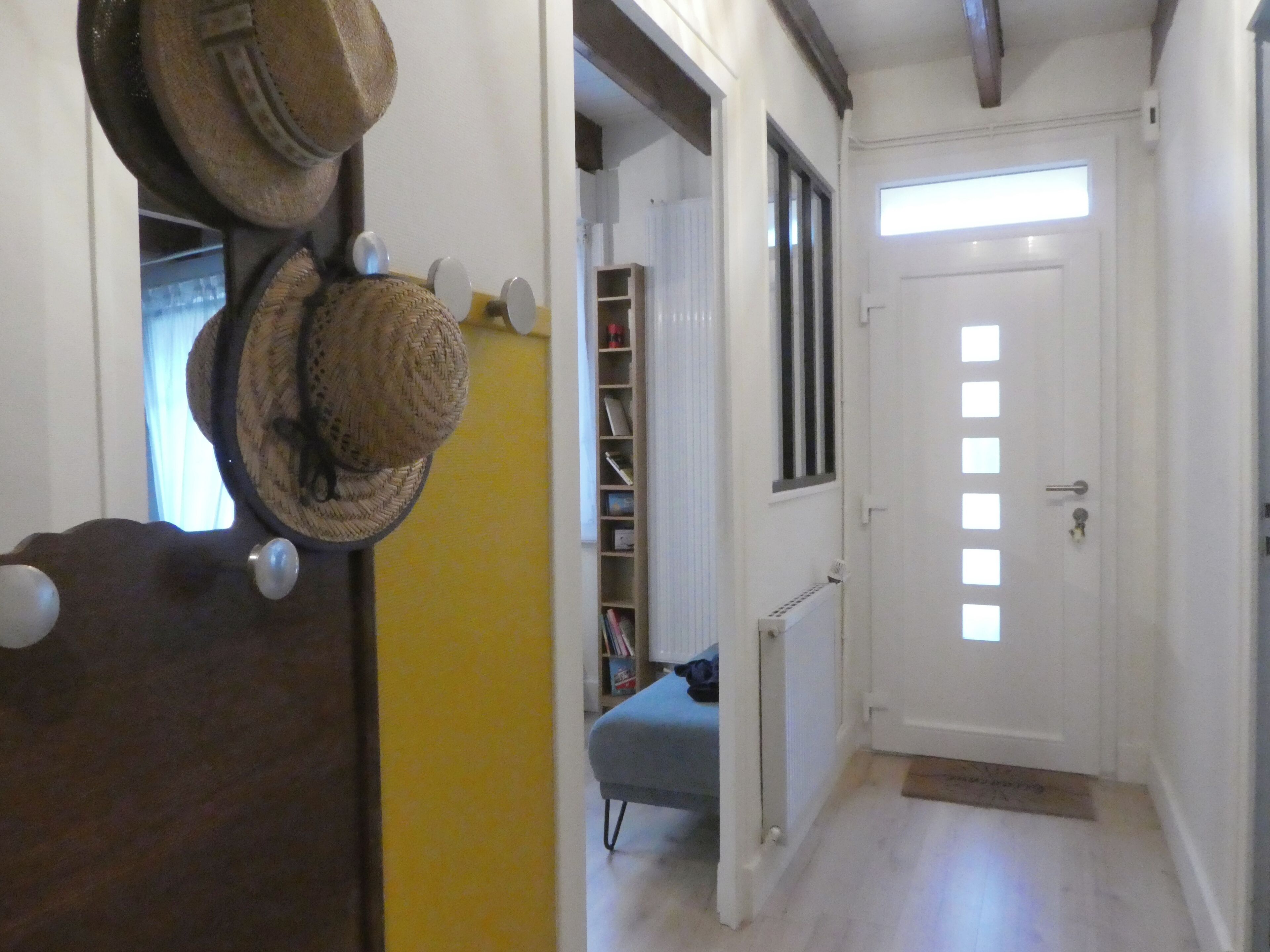 A hallway with a white door, a radiator, and a shelf with books.