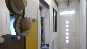 Un pasillo con una puerta blanca, un radiador y una estantería con libros.