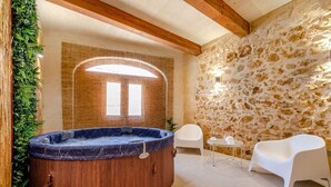 A spa room with a wooden hot tub, white chairs, and a stone wall. - Escape w/Private pool, indoor hot tub & BBQ terrace (Ix-Xaghra)