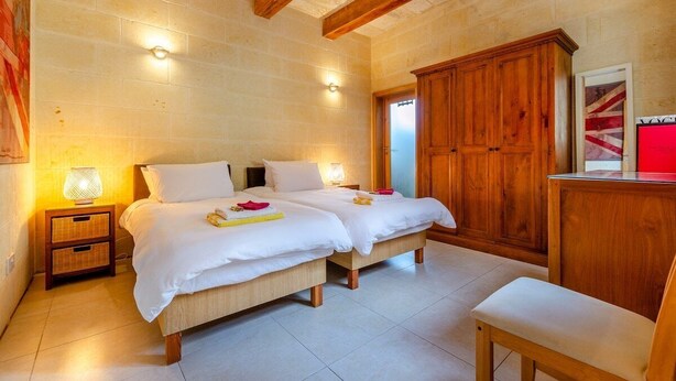 A bedroom with two beds, wooden wardrobe, and a small desk with a red object on it. - Escape w/Private pool, indoor hot tub & BBQ terrace (Ix-Xaghra)