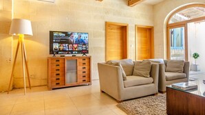 A living room with a television, two sofas, a lamp, and a wooden cabinet. - Escape w/Private pool, indoor hot tub & BBQ terrace (Ix-Xaghra)