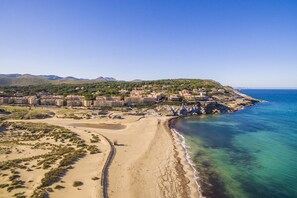 Ein Küstenresort mit Strandvillen, einem Sandstrand und einem Bergpanorama.