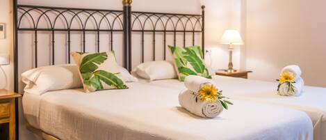 A hotel room with a bed, two pillows, a nightstand, a lamp, and a painting on the wall.