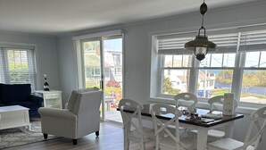 A spacious living room with a dining area, large windows, and a view of the outdoors.