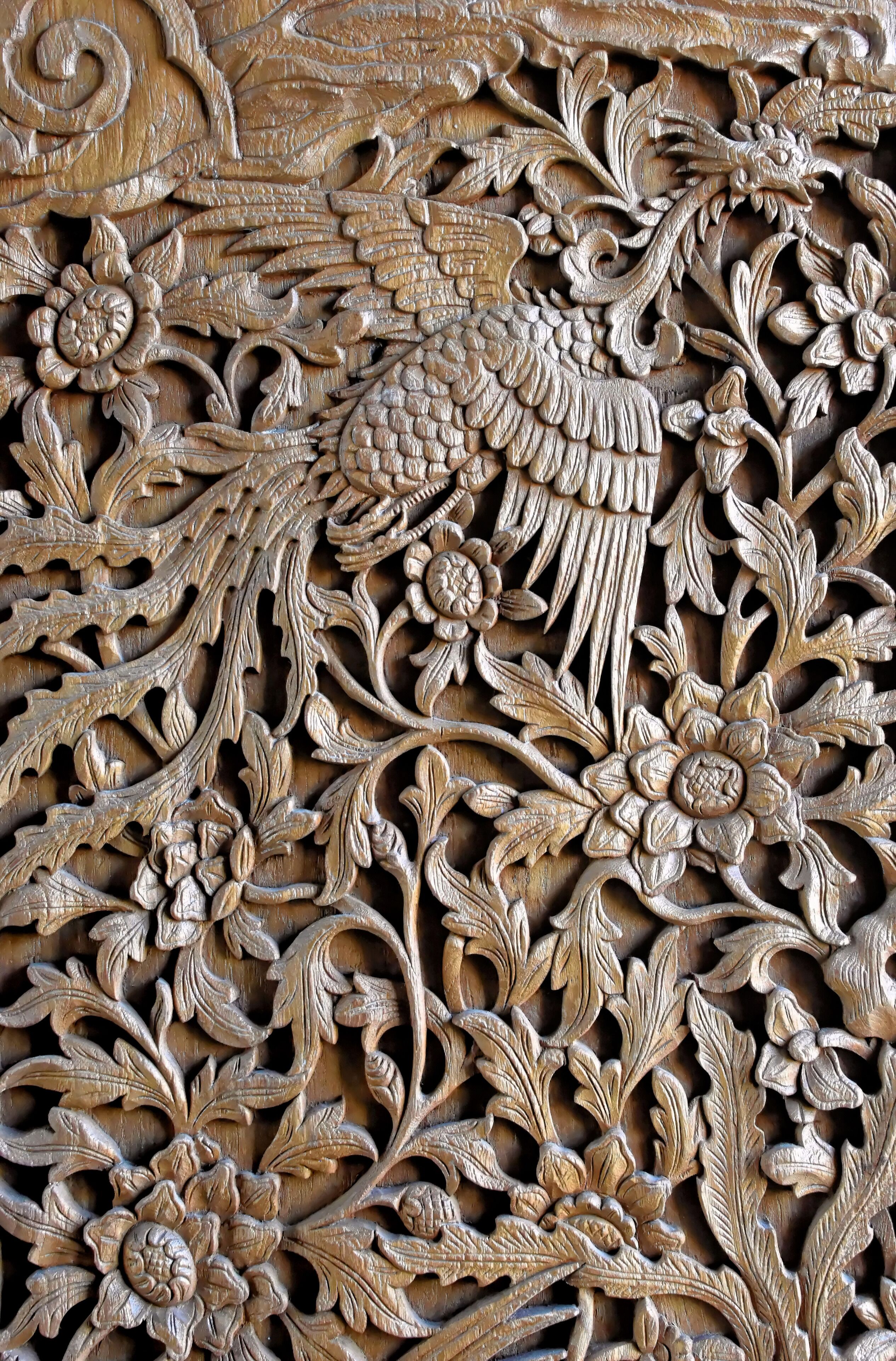 Un panel de madera tallada con detalle, con motivos florales y de hojas.