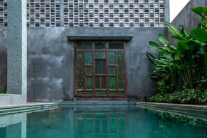 A pool with a traditional wooden door and a concrete wall with a grid pattern.