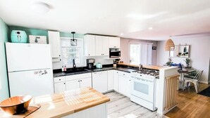 A compact kitchen with white cabinets, a stainless steel stove, and a wooden countertop. - A relaxing family home with a fenced in backyard (Yarmouth)