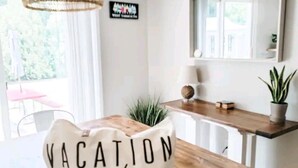 A dining area with a wooden table, a wicker pendant light, a potted plant, and a sign that reads "VACATION mode". - A relaxing family home with a fenced in backyard (Yarmouth)