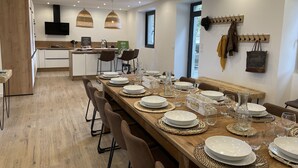 Un'area pranzo moderna con un lungo tavolo in legno apparecchiato per un pasto, circondato da sedie.