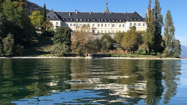Un grande edificio storico dalla facciata simmetrica, affacciato su un lago tranquillo.