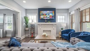 A living room with a fireplace, a television mounted above it, and a sofa. - 3 bedroom 1 bath house-Free Parking-10 min to EWR. (Irvington)