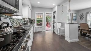 A kitchen with a stove, microwave, and a dining area with chairs. - 3 bedroom 1 bath house-Free Parking-10 min to EWR. (Irvington)