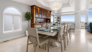 A spacious dining area with a large table set for six, surrounded by chairs. - Luxury Oceanfront Vacation Home on Hollywood Beach (Oxnard)