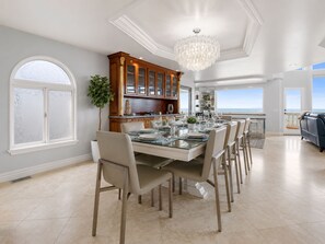 A spacious dining area with a large table set for six, surrounded by chairs. - Luxury Oceanfront Vacation Home on Hollywood Beach (Oxnard)