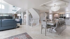 A spacious living area with a modern kitchen, a dining table, and a staircase leading to an upper level. - Luxury Oceanfront Vacation Home on Hollywood Beach (Oxnard)