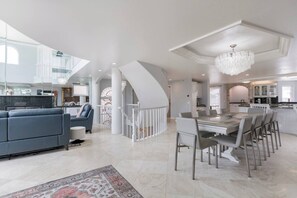 Un vaste espace de vie comprenant une cuisine moderne, une table à manger et un escalier menant à l’étage supérieur.