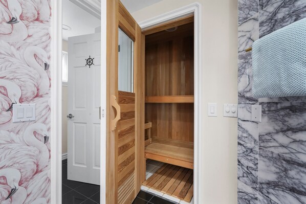Une pièce avec une armoire en bois, une porte blanche ornée d’un motif de roue de navire et un mur imitant le marbre.