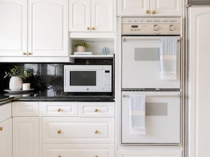A kitchen with white cabinets, a microwave, and a double oven. - Luxury Oceanfront Vacation Home on Hollywood Beach (Oxnard)