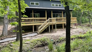 Une cabane dotée d’une terrasse en bois et d’un escalier menant à un porche abrité.