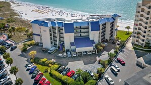 Ein Hotel mit Blick auf den Strand, mehreren Etagen und einem Parkplatz.