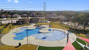 A swimming pool with a unique design, surrounded by a landscaped area with pathways and seating. - Spacious Cozy Austin Home with Pool Access (Austin)