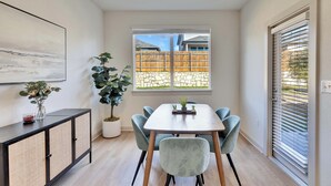A dining area with a table, chairs, a potted plant, and a window with a view of a backyard. - Spacious Cozy Austin Home with Pool Access (Austin)
