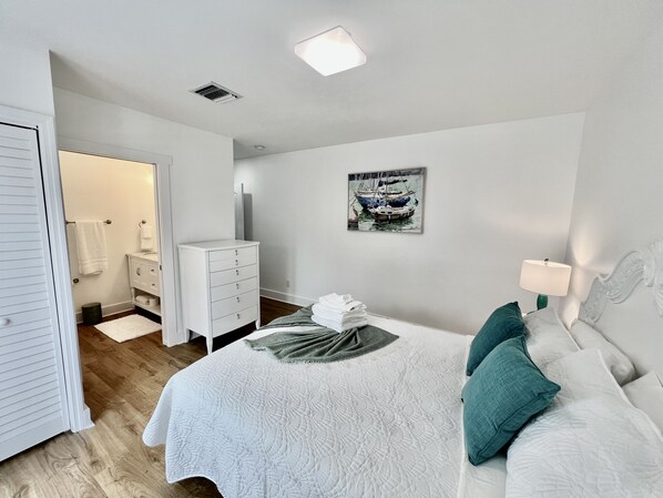 Un dormitorio con cama, cómoda, un cuadro y mesita de noche.
