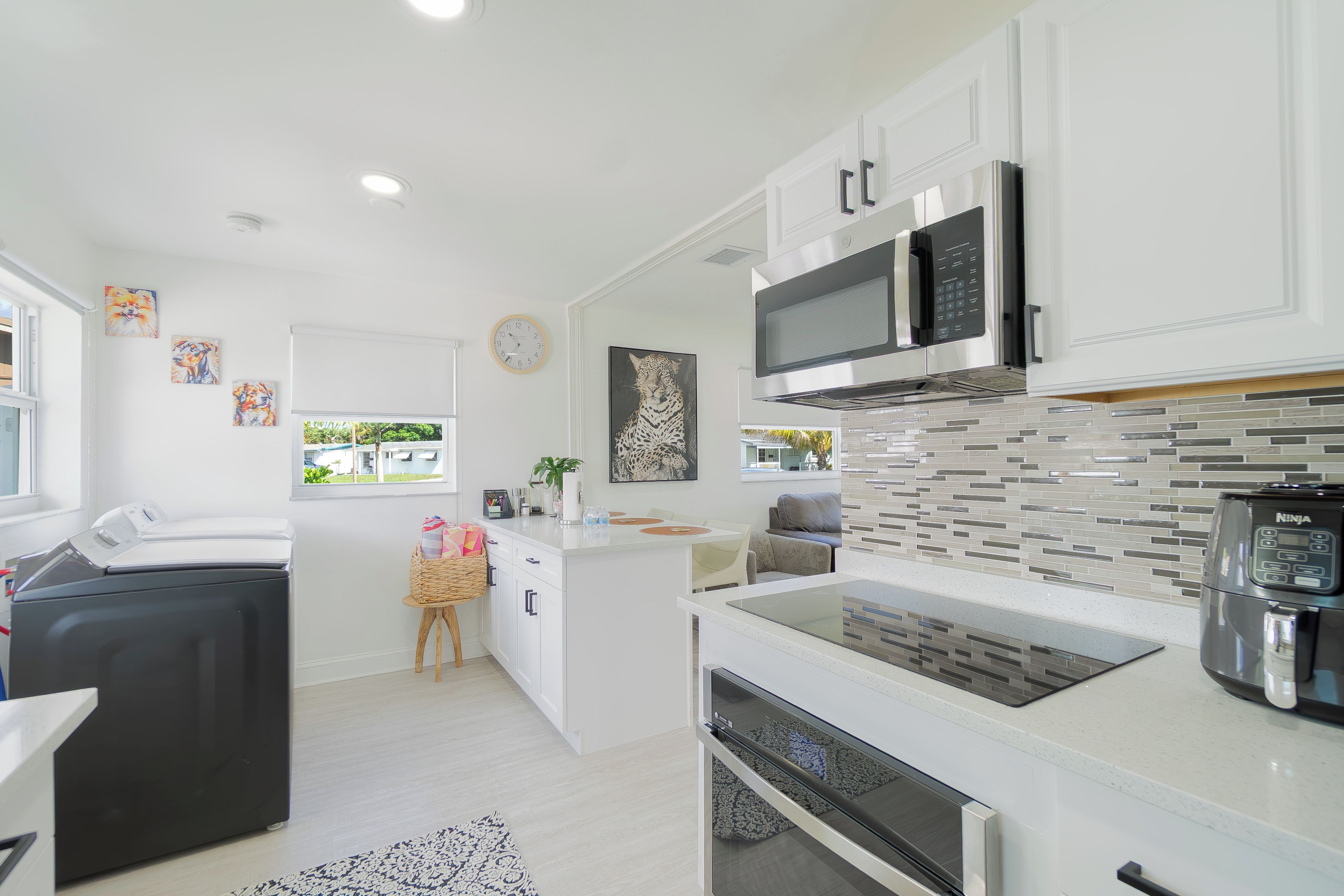 A modern kitchen with white cabinetry, a built-in microwave, and a coffee machine.