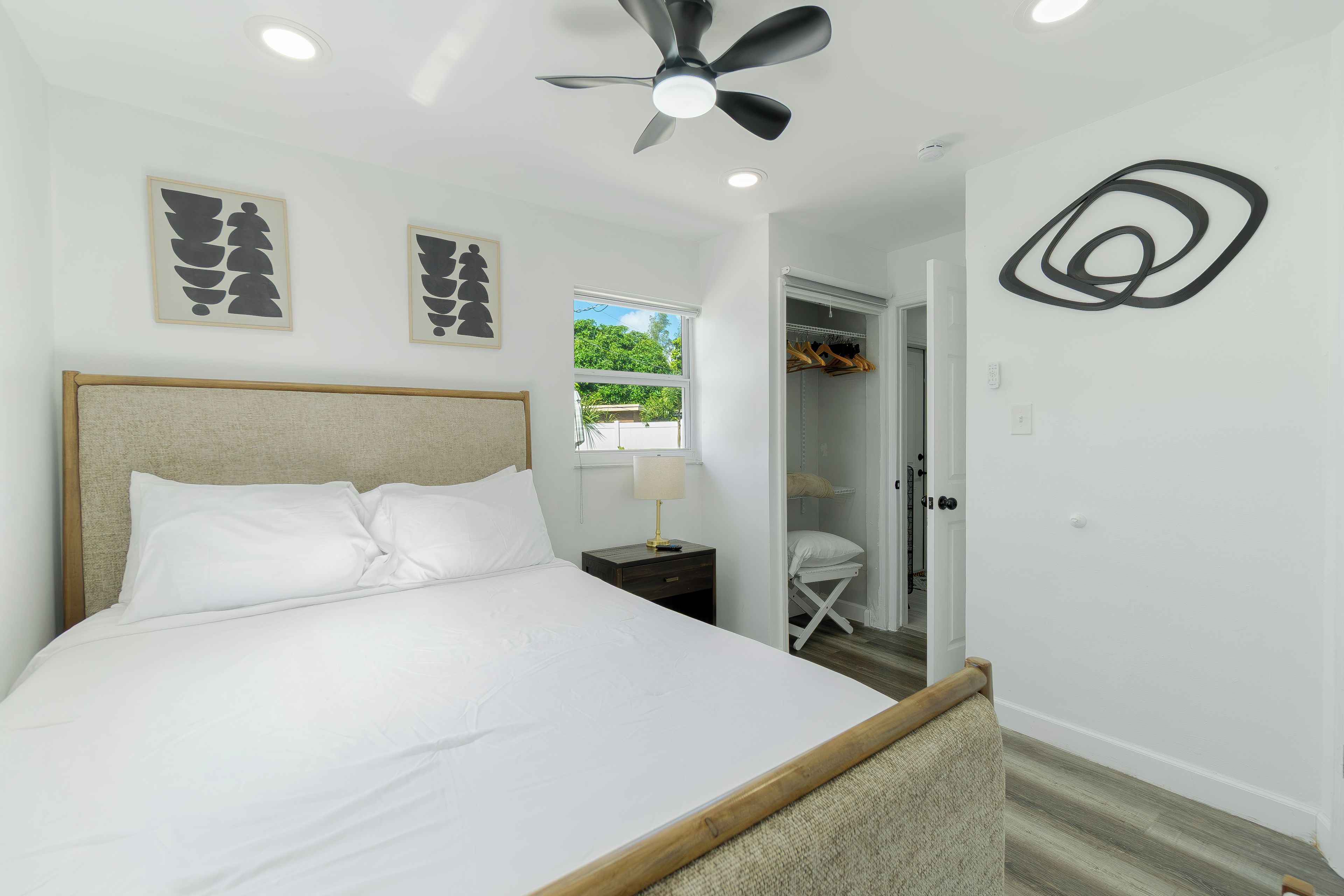 A bedroom with a bed, a ceiling fan, a window, and a closet.