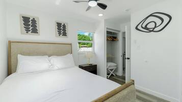 A bedroom with a bed, a ceiling fan, a window, and a closet.