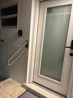 Une porte dotée d’un panneau en verre dépoli, d’une poignée en métal et d’un petit appareil électronique fixé au mur.