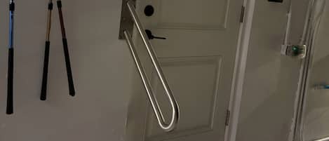 A door with a metal handle and a keyhole, a doormat with a palm tree logo, and a wall-mounted towel rack with towels.