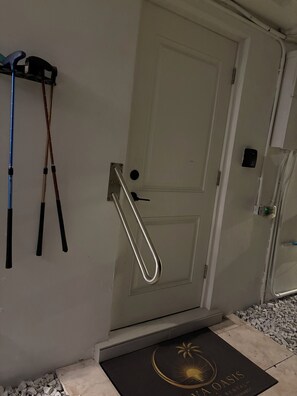 Eine Tür mit einer Metallklinke und Schlüsselloch, eine Fußmatte mit Palmenlogo und ein an der Wand befestigter Handtuchhalter mit Handtüchern.