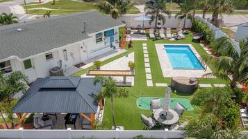 A residential property with a swimming pool, outdoor seating, and a covered patio area.