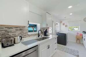 A modern kitchen with a dishwasher, a coffee maker, and a toaster.