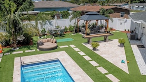 Un jardin avec une piscine, un kiosque et un espace salon extérieur.