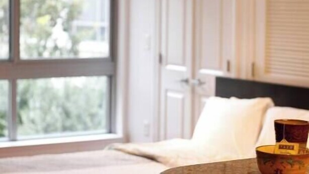 A bedroom with a large window, a bed, and a nightstand with a lamp. - Luxury Downtown DC Apartment - Near City Center (Washington)