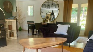 Ein modernes Wohnzimmer mit einem Holztisch, zwei Sofas, einem Essbereich und einem großen Spiegel.