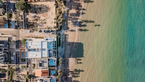 Eine Vogelperspektive zeigt ein Küstenhotel mit mehreren Gebäuden, einem Strand und freiem Blick auf den Ozean.