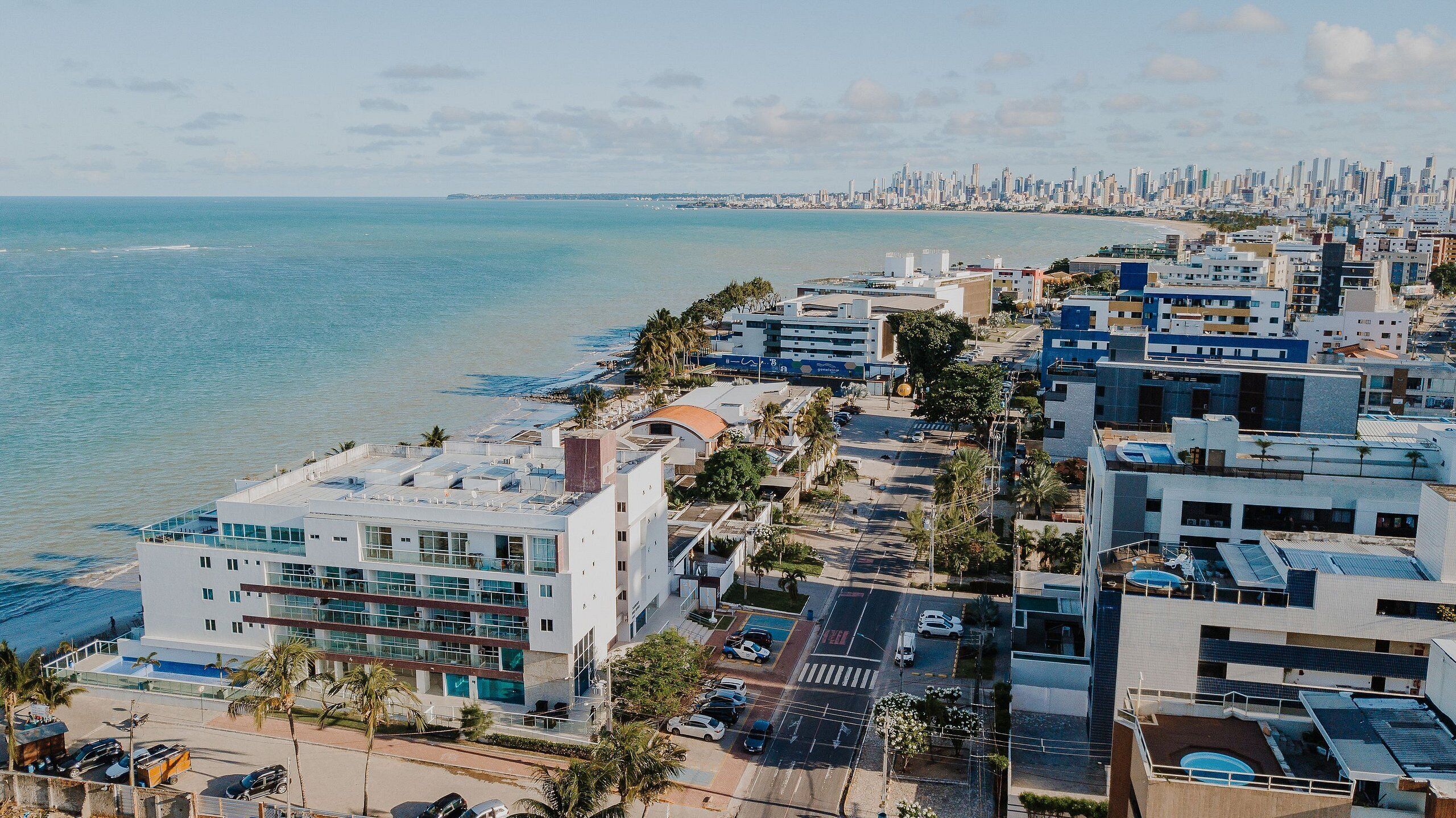 A coastal cityscape with modern buildings, a beach, and a distant skyline.