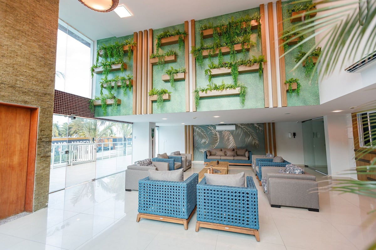 A spacious lobby with a high ceiling, a seating area with blue and grey sofas, and a green wall with vertical planters.