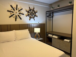 A hotel room with a bed, a nightstand with a lamp, a wardrobe, and two wall decorations. - Flamboyant Caribessa (João Pessoa)