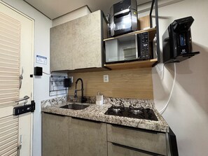 A compact kitchen with a granite countertop, a built-in microwave, a coffee maker, and a stove. - Flamboyant Caribessa (João Pessoa)