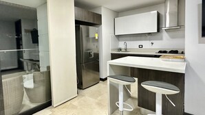 Eine moderne Küche mit einem Edelstahlkühlschrank, einer weißen Arbeitsplatte und zwei Barhocker.
