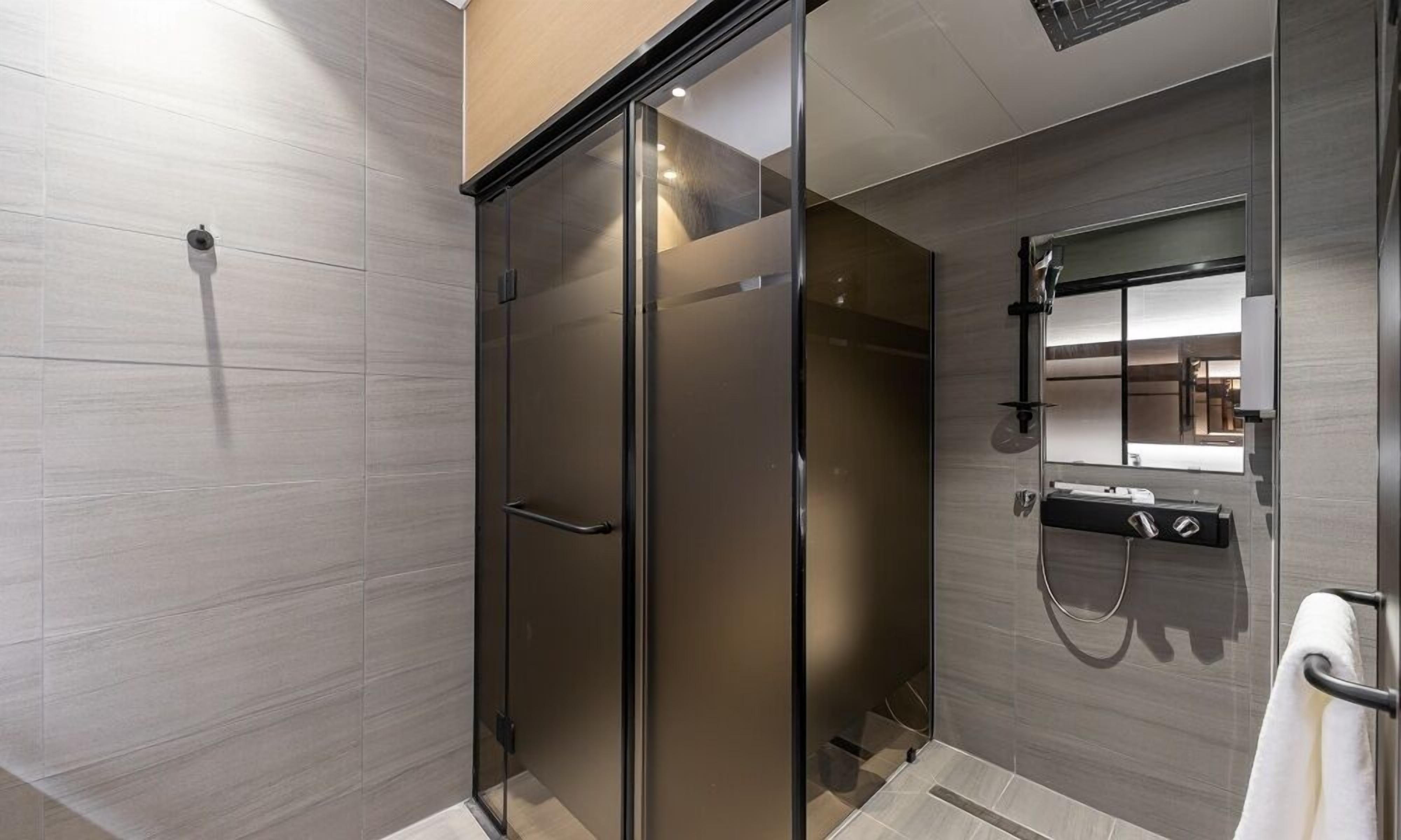 Un baño moderno con cabina de ducha de vidrio, lavabo integrado con espejo y un perchero.